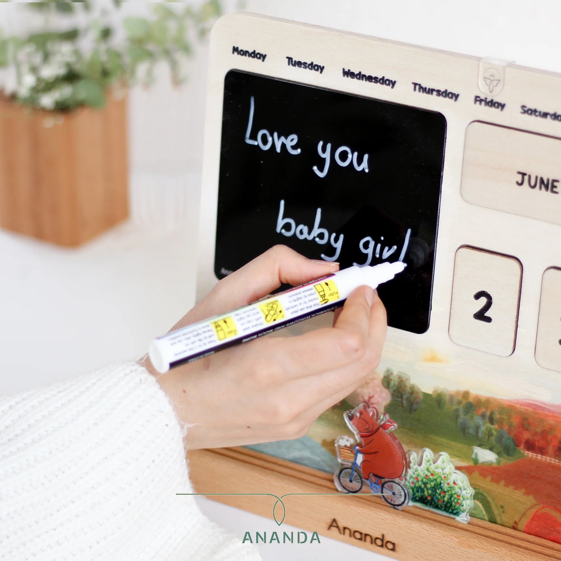 Writing on the black plexiglass board of the Hannah perpetual calendar using the included chalk marker — customizable and reusable for daily updates