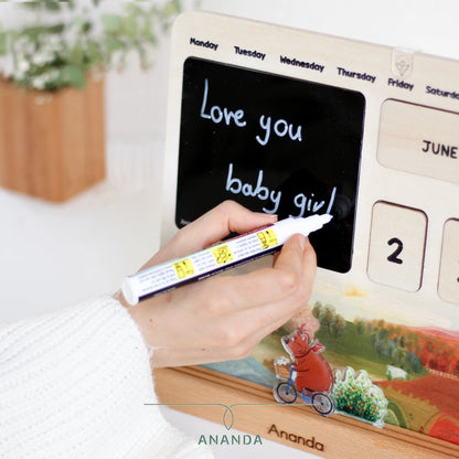 Writing on the black plexiglass board of the Hannah perpetual calendar using the included chalk marker — customizable and reusable for daily updates